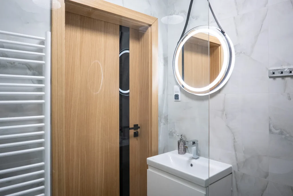 Minimalistyczna łazienka z dużym lustrem i jasnym wykończeniem