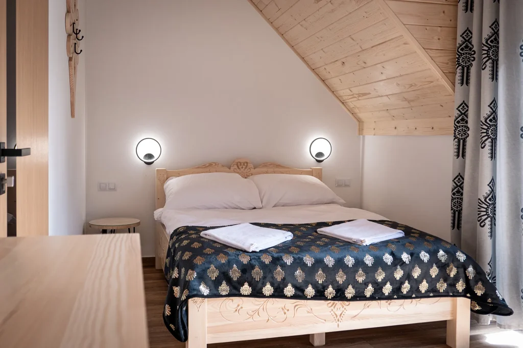 Drewniana sypialnia z tradycyjnymi firankami i nastrojowym oświetleniem